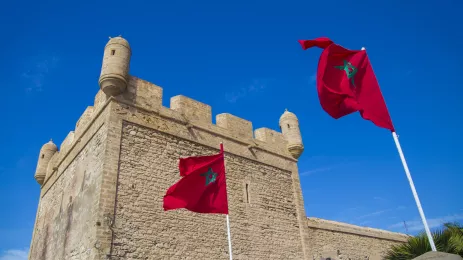 Two red flags flying by the turret of a fort