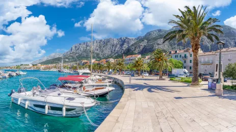 Makarska harbor under a blue cloudy sky, surrounded by the Croatia mountain range