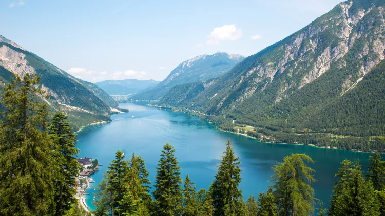 Alpine lake with fir trees and distant mountains  in Tyrol, Austria