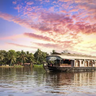 Ship cruising along the waters, with a colourful blue and purple sunset approaching