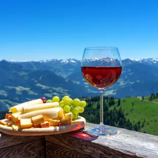 Fresh tirol cheese with wine and grapes over mountain landscape