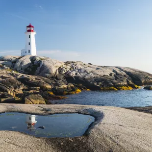 Peggys Cove Lighthouse with rocks and glistening water in Nova Scotia, Canada