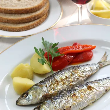 Charcoal grilled sardines with boiled potatoes and peppers with a side of red wine