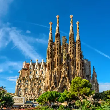 The La Sagrada Familia cathedral in Barcelona against a bright blue sky on a sunny day.