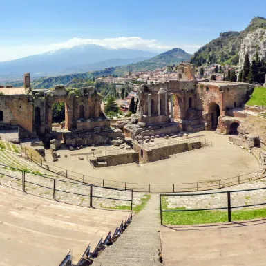 Ancient greek theatre ruins with views of Mount Etna in Taormina, Italy