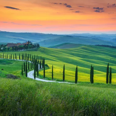 Green grassy hills and curved road of Crete Senesi Asciano in Tuscany