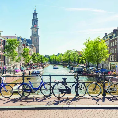 A view over a canal from a bridge with bicycles, boats and the Westerkerk in the back, Amsterdam.