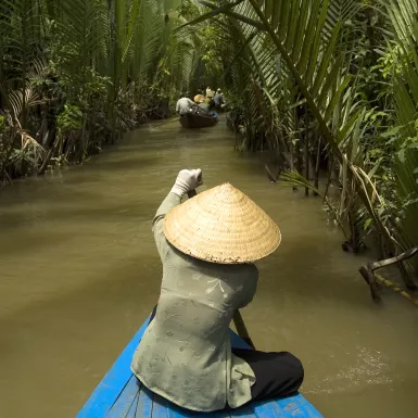 Vietnamese woman rowing a boat on the Mekong River in Vietnam