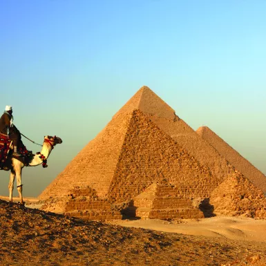 A landscape shot of a Bedouin camel rider overlooking the Great Pyramid of Giza