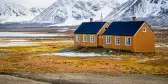 Yellow houses on yellow tundra grass with snowy mountains in Svalbard, Norwegian Arctic