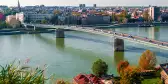 Aerial of Novi Sad's Varadin Bridge spanning across the Danube River, with a background of the cityscape