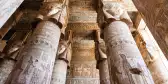 Pillars inside Hypostyle Hall at the Dendera Temple, featuring faded hieroglyphics 