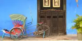 Tricycle parked in front of large brown door in Penang, Malaysia