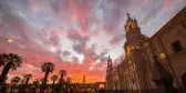 Stunning colorful sky and clouds at dusk in Arequipa, famous travel destination and landmark in Peru. Wide angle view from below of the colonial Cathedral. Panoramic frame.