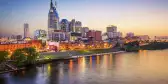 Nashville downtown skyline before sunset along a clear sky, it's reflection displayed in the foreground of the Cumberland River.