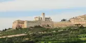 Landscape view of Saint Francis Cathedral surrounded by vegetation in Assisi, Italy.