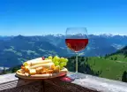 Fresh tirol cheese with wine and grapes over mountain landscape