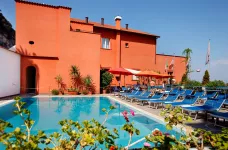 Poolside view of Hotel Villa Maria exterior featuring blue sun loungers