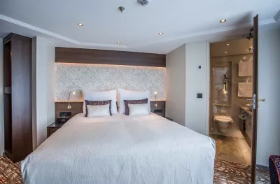 Interior shot of bedroom with bathroom aboard the Oscar Wilde cruise ship