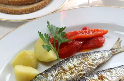 Charcoal grilled sardines with boiled potatoes and peppers with a side of red wine