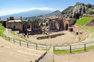 Ancient greek theatre ruins with views of Mount Etna in Taormina, Italy