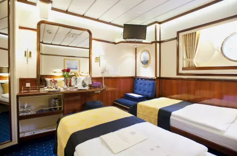 Brightly lit Star Flyer cabin room featuring two single beds and a porthole window