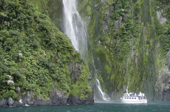 Ship near Waterfall with lush vegetation in New Zealand