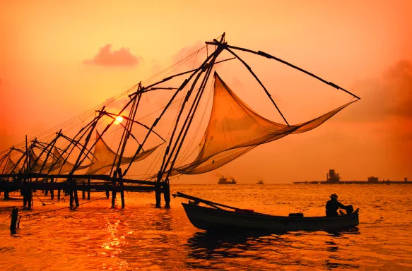 A sunset over fishing nets and boat in Cochin (Kochi), India