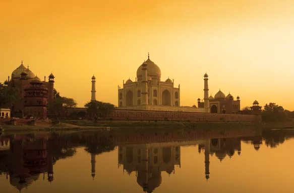 Taj Mahal at sunset reflected in the calm Yamuna river in India