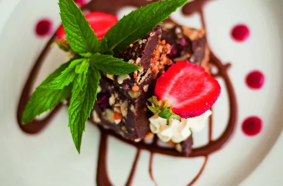 Close-up of chocolate dessert with chocolate sauce decoration, strawberries and mint