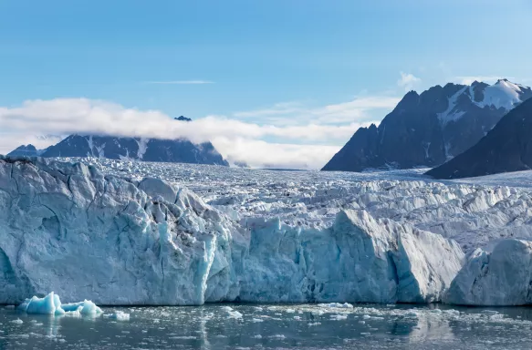 The Monacobreen Glacier with distant mountains in Svalbard, Norway