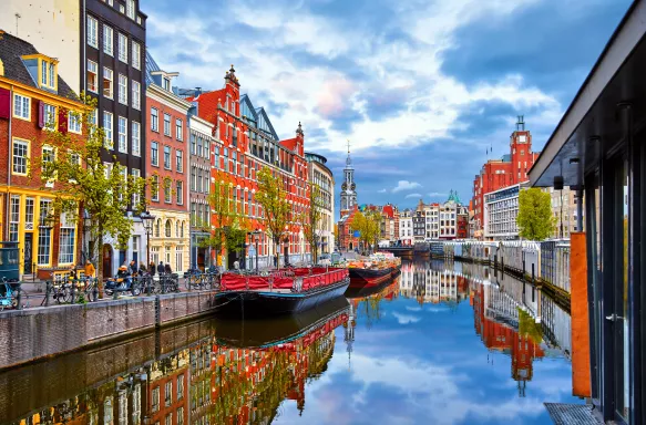 The Amstel River in the Netherlands, boats on the water with colourful houses overlooking the canal