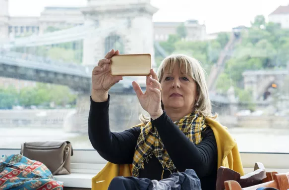 Senior woman sitting in a deck cabin of a cruise ship and exploring the city.