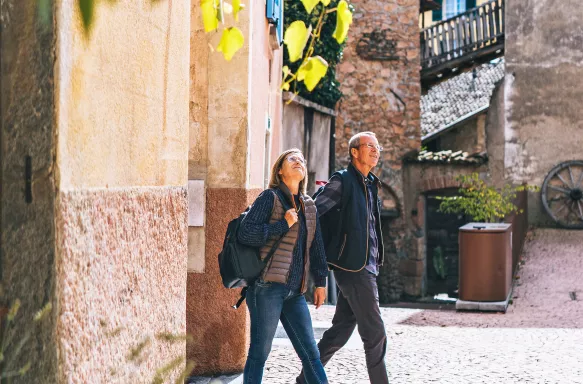 Mature couple walking and holding hands through a sunny European city