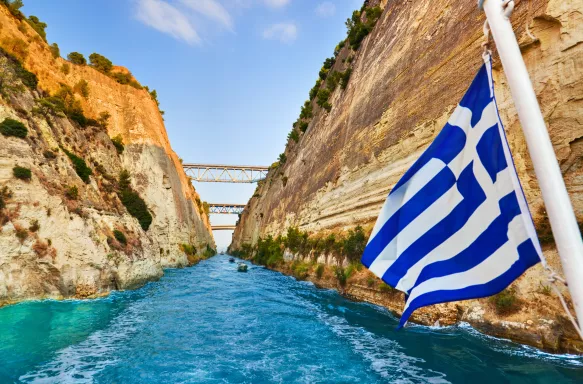 Corinth channel with Greek flag blowing in wind on ship in Greece 