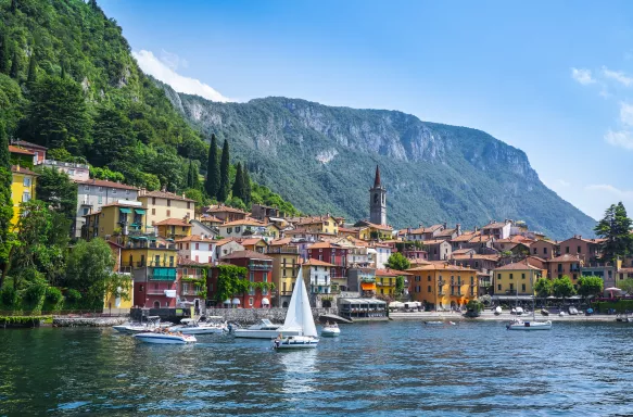 View of traditional Varenna village on lake Como. Lombardy, Italy. Small boats on lake with Italian-style houses in the background.