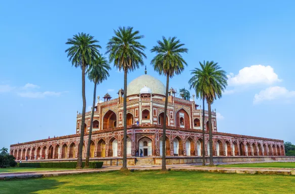 Front view of Humayun's Tomb with tall palm trees in Delhi, India