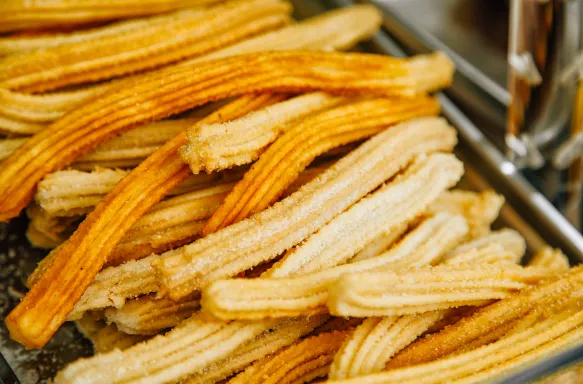 Close-up of a pile of Spanish churros, coated in sugar.