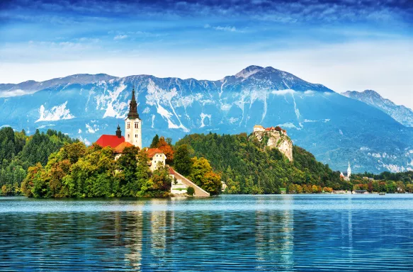 Church on the Island and ancient castle on top of a rock with European Alps in background at Lake Bled, Slovenia