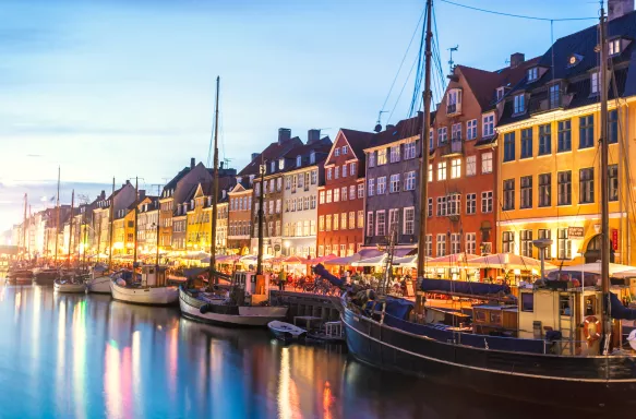 Rows of colourful houses overlooking boats on the Nyhavn canal at night in Copenhagen, Denmark