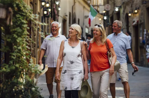 Mature couples looking around old town Italy as evening draws in.  Little lights can be seen outside of the buildings.