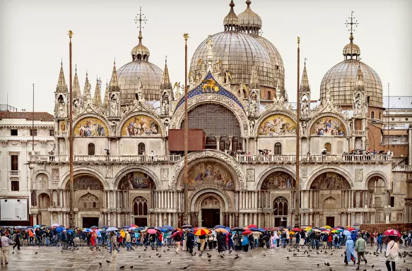 St. Mark's Basilica and tourists with colourful umbrellas in Venice, Italy