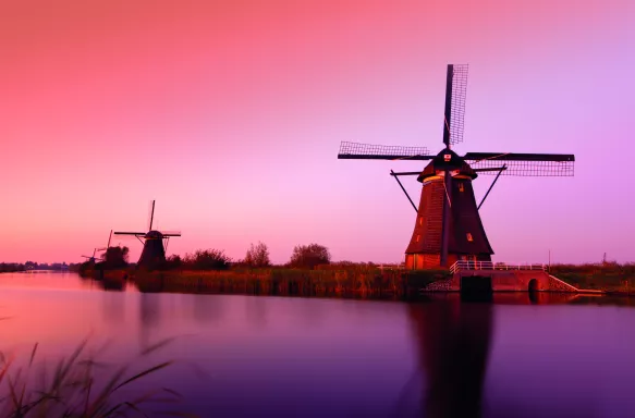 A pink sunset over the Lek River and Kinderdijk windmill monuments, South Holland, Netherlands