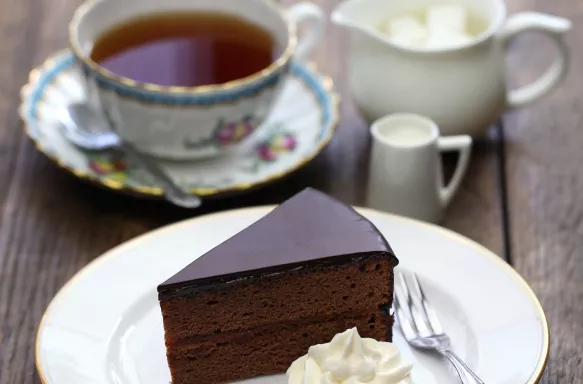 Homemade sachertorte, Austrian chocolate cake with a dollop of whipped cream and some tea 