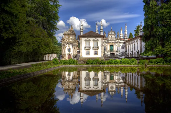 Mateus Palace by a decorative pond, it's reflection mirrored in the water, Portugal