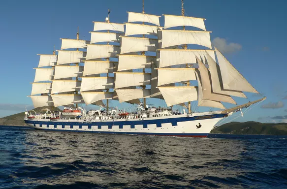 Exterior side shot of the Royal Clipper ship with tall sails cruising the ocean