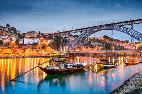 Rabelo boats on the Douro River and Porto skyline illuminated at night in Portugal