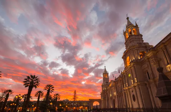 Stunning colorful sky and clouds at dusk in Arequipa, famous travel destination and landmark in Peru. Wide angle view from below of the colonial Cathedral. Panoramic frame.