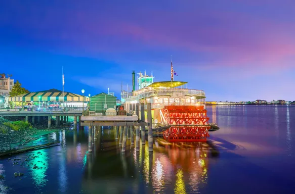 Paddle steamer in Mississippi river in New Orleans, Lousiana. Surrounded by colourful lights reflecting on the river.