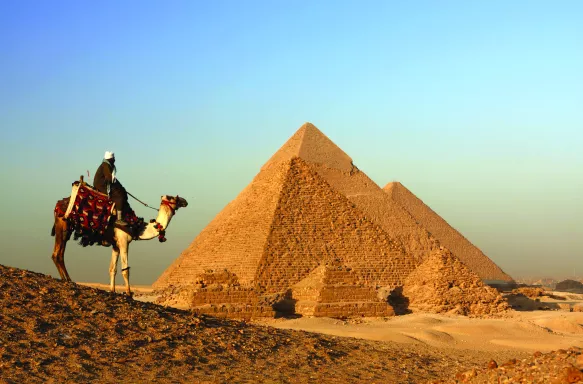 A landscape shot of a Bedouin camel rider overlooking the Great Pyramid of Giza